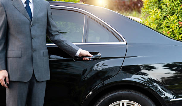 unrecognizable well dressed male chauffeur opening a car door