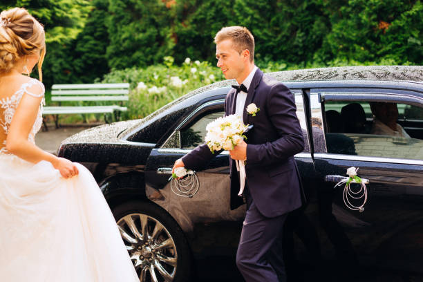 the groom opens before bride door to a chic black car